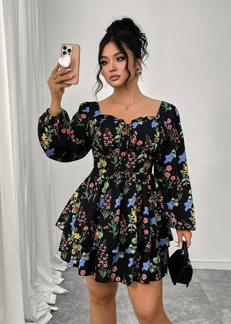 Woman wearing a black floral dress taking a mirror selfie.