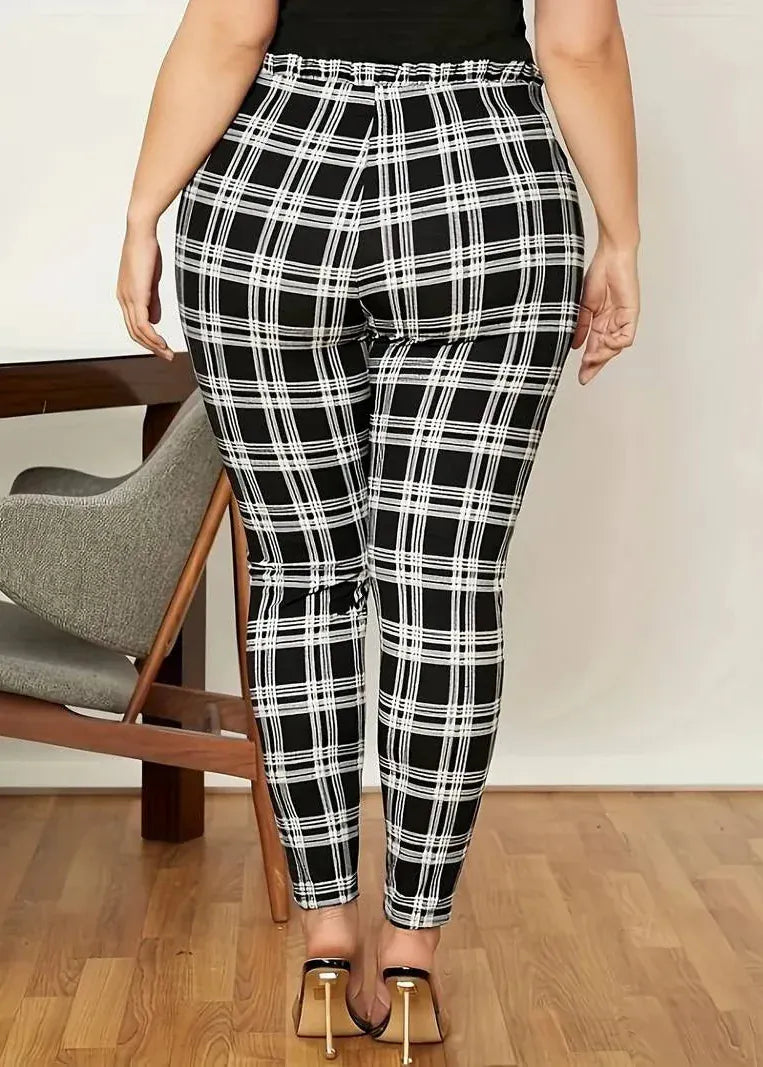 Person wearing black and white plaid pants in a room with a chair and wooden floor.