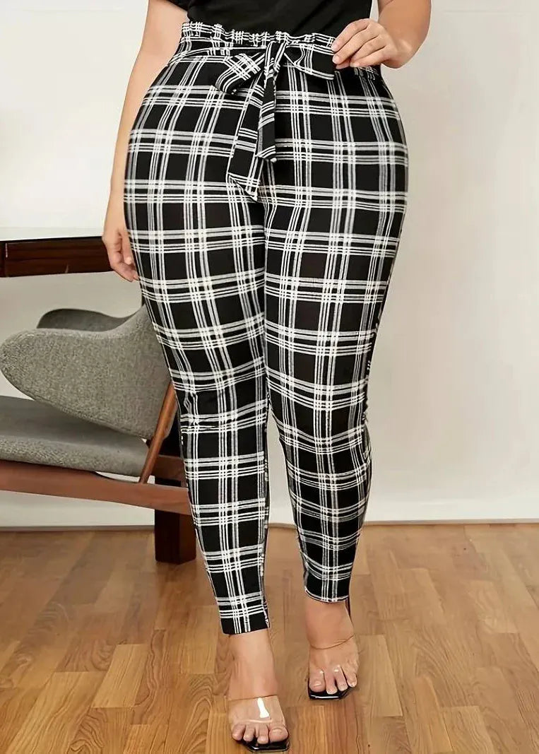Person wearing black and white plaid pants indoors on a wooden floor.