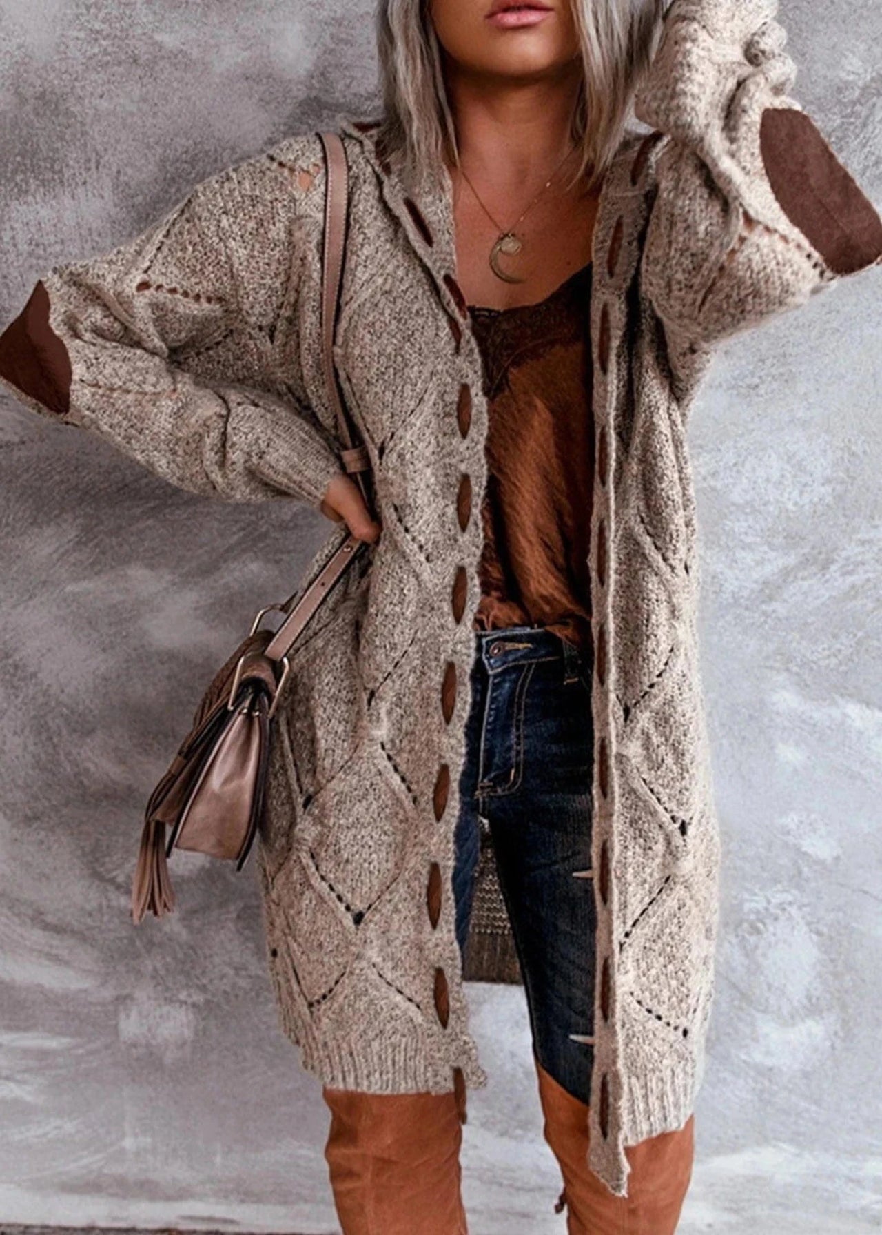 Person wearing a long beige cardigan with brown accents against a gray background