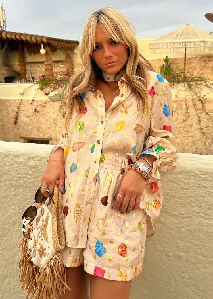 Woman wearing a colorful outfit with a patterned shirt and shorts, standing outdoors.