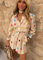 Woman wearing a colorful patterned dress against a stone wall.