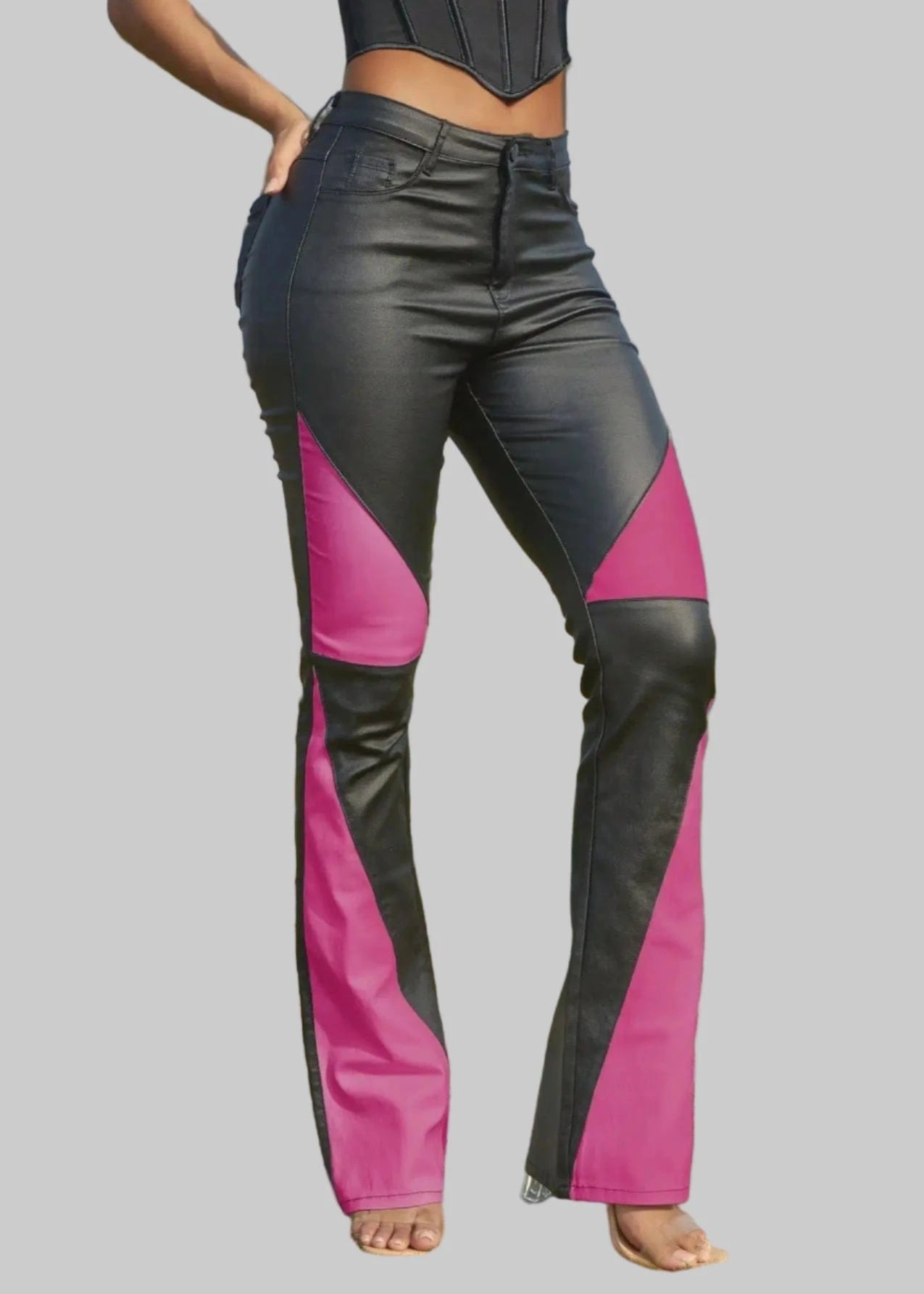 Person wearing black and pink riding pants on a grassy field with palm trees in the background