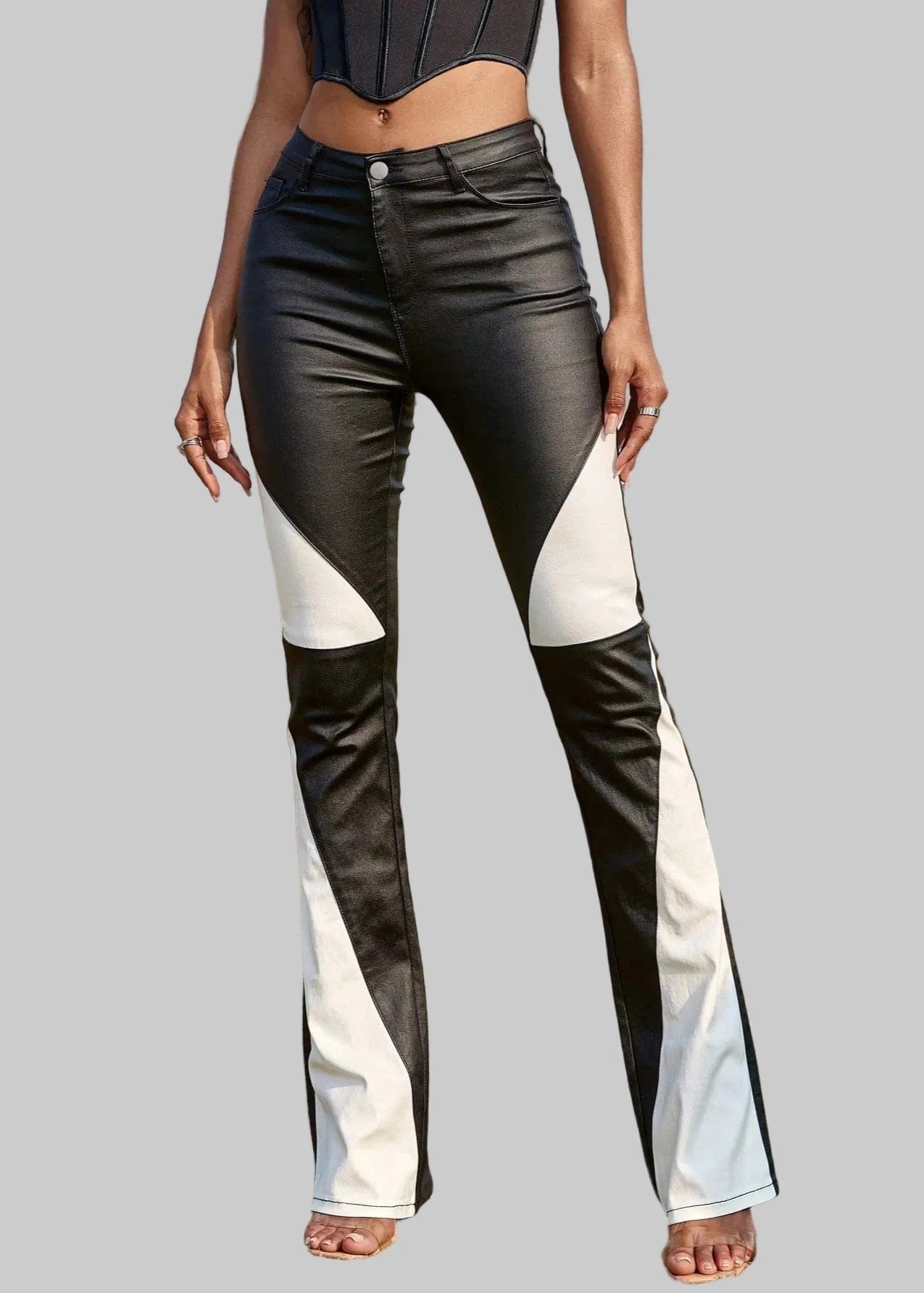 Person wearing black and white flared jeans on a grassy field with palm trees in the background.