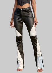 Person wearing black and white flared jeans on a grassy field with palm trees in the background.
