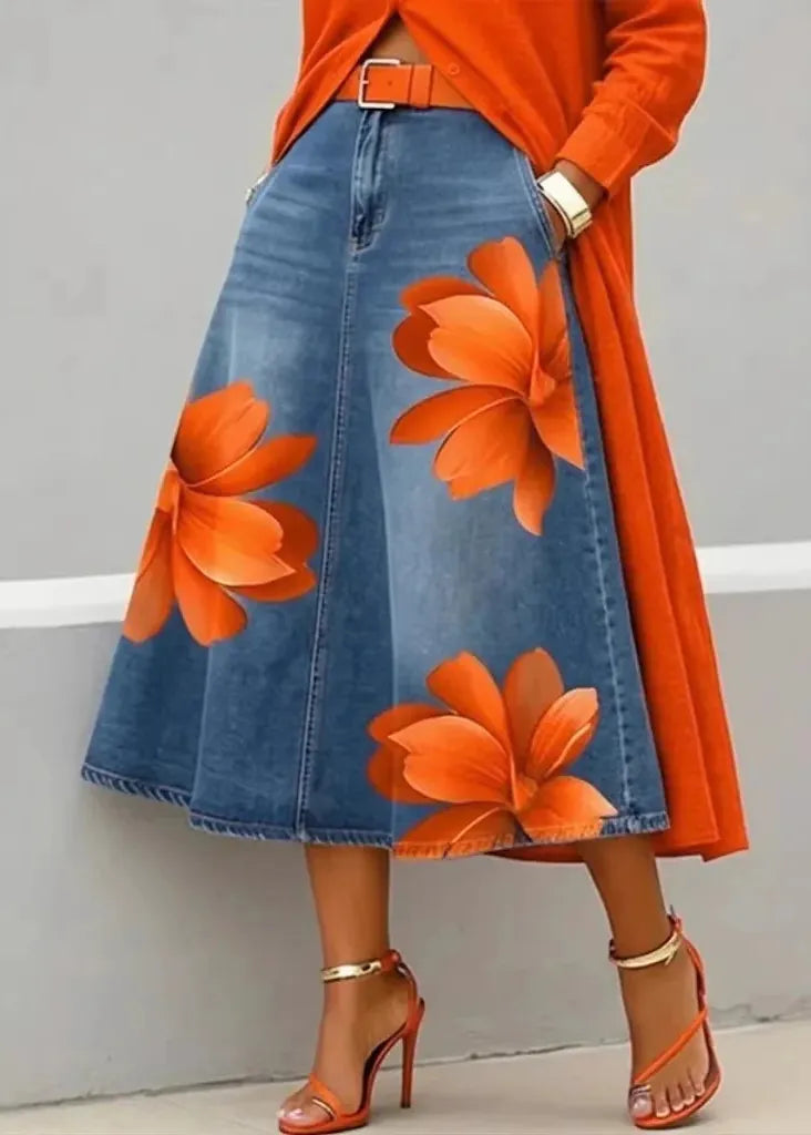 Person wearing an orange floral denim skirt with a matching top against a gray background