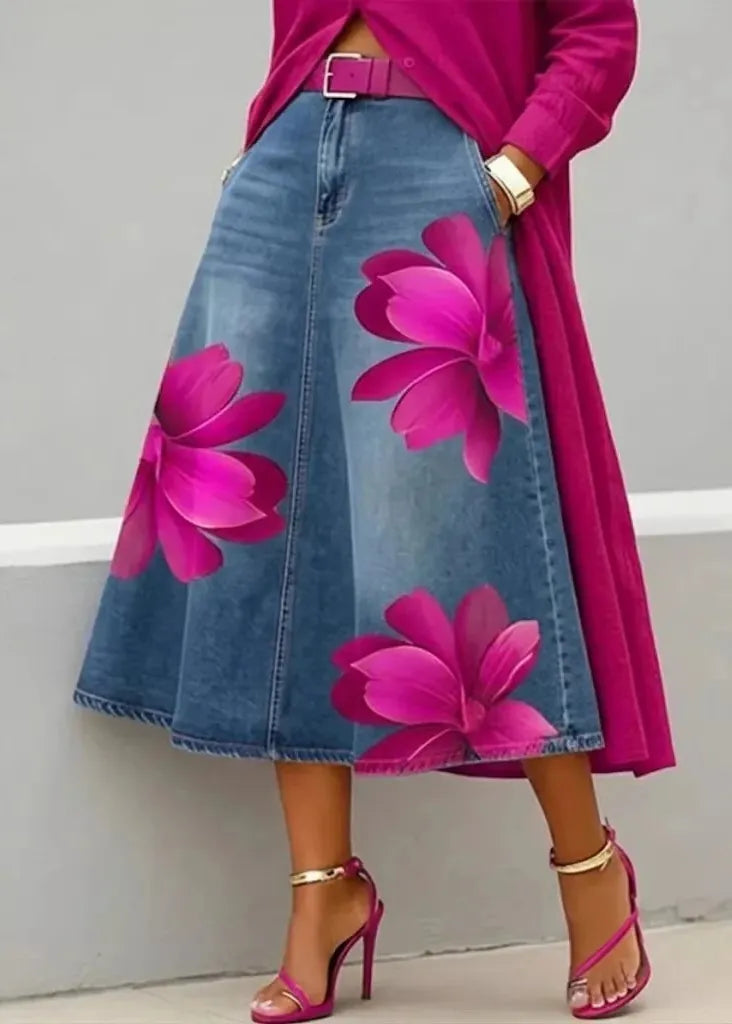 Person wearing a denim skirt with pink floral designs and a pink top against a gray background