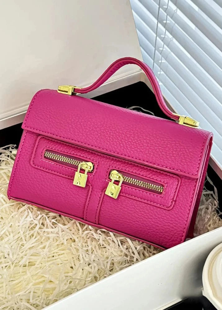 Pink handbag with gold zippers on a white surface
