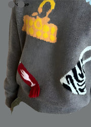 Gray sweater with colorful graphic designs on a wooden floor background