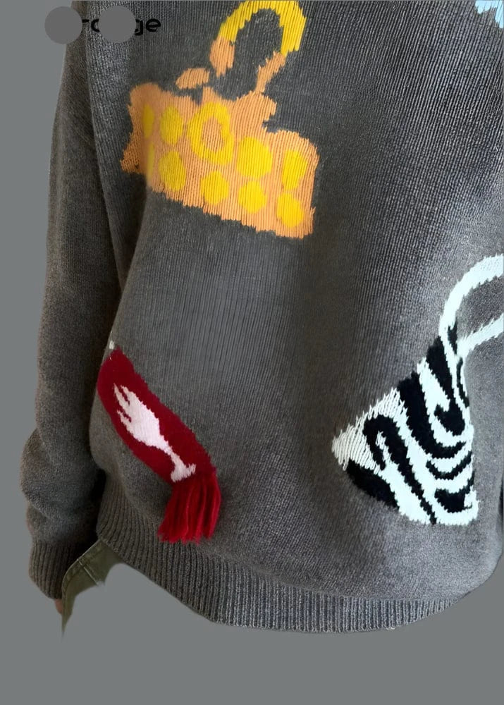 Gray sweater with colorful graphic designs on a wooden floor background