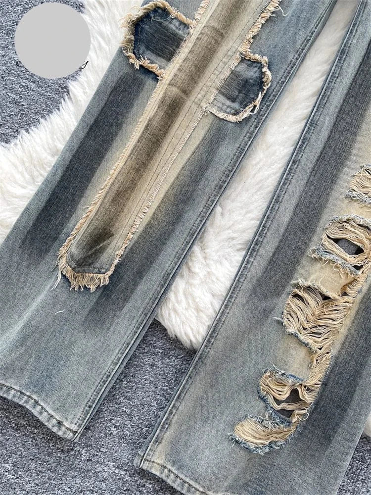 Close-up of distressed denim jeans with raw edges on a textured surface.