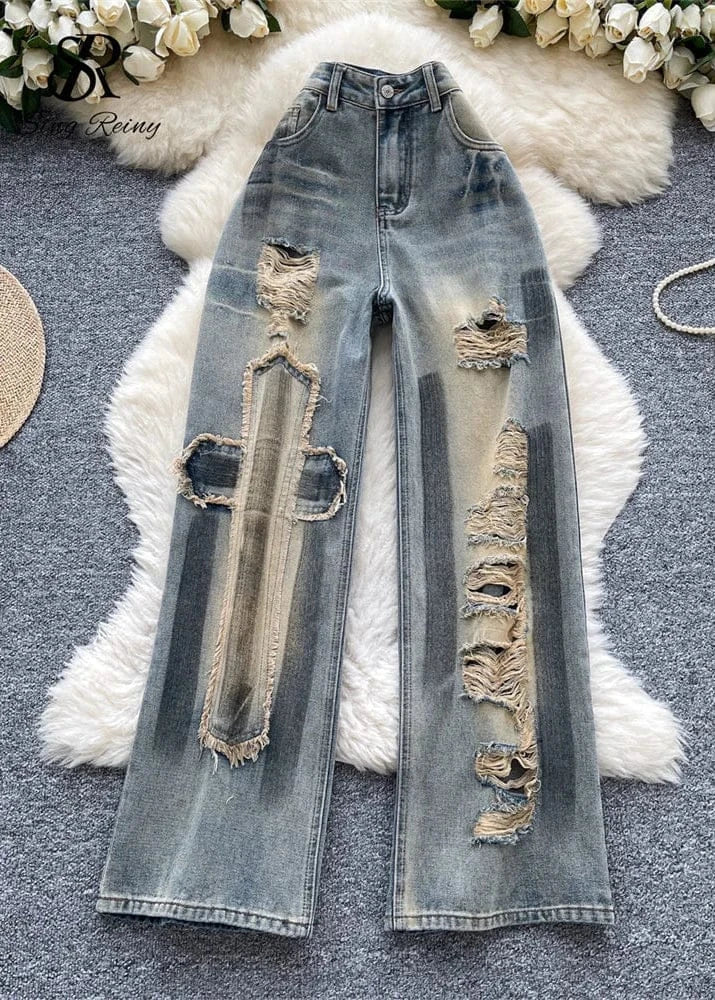 Distressed blue jeans on a textured surface with floral decorations