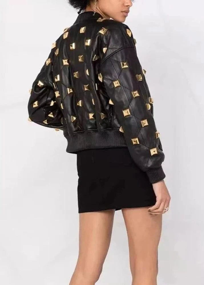 Black leather jacket with gold studs worn by a person on a white background
