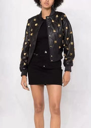 Person wearing a black jacket with gold patterns on a white background
