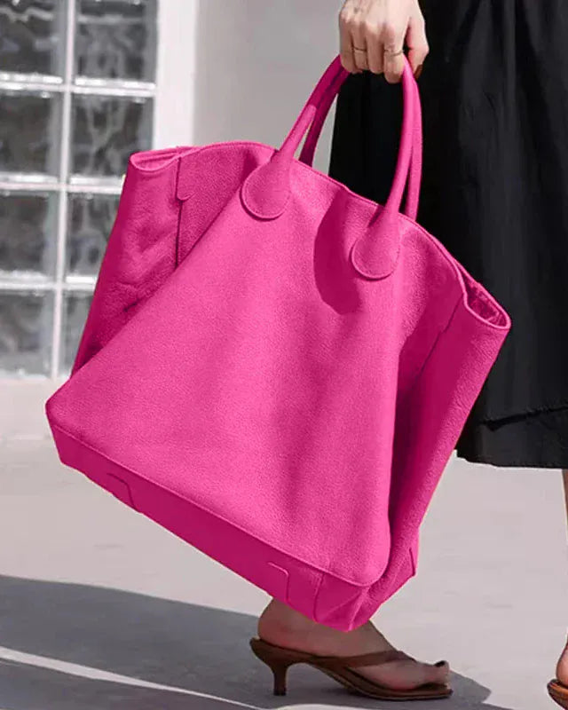 Person holding a bright pink tote bag outdoors