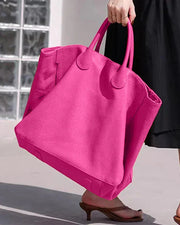 Person holding a bright pink tote bag outdoors
