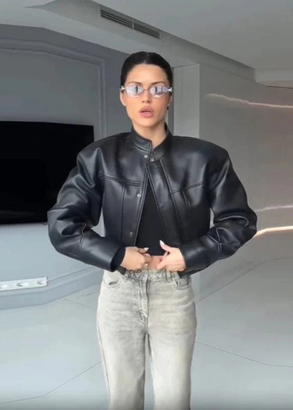 Person wearing a black leather jacket and light gray pants in an indoor setting