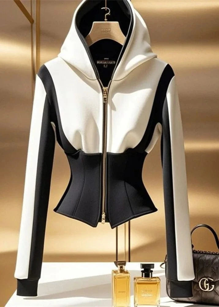 White and black hoodie on a gold background with a handbag and perfume bottles.