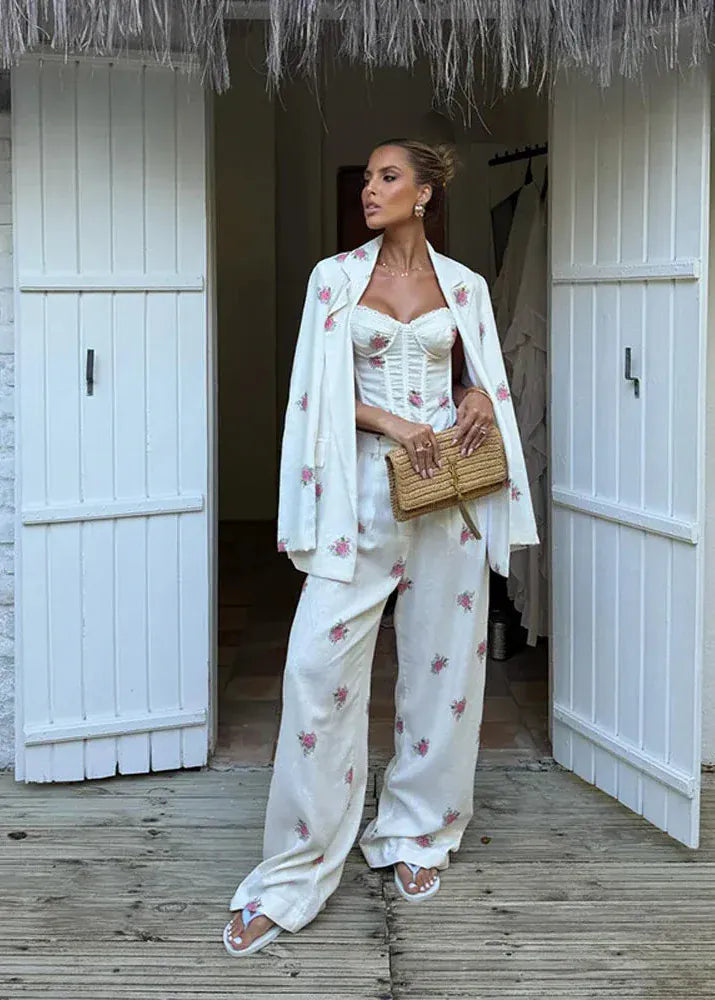 Woman in a white floral outfit standing in a doorway of a white building.