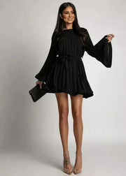 Woman wearing a black dress with long sleeves on a plain background