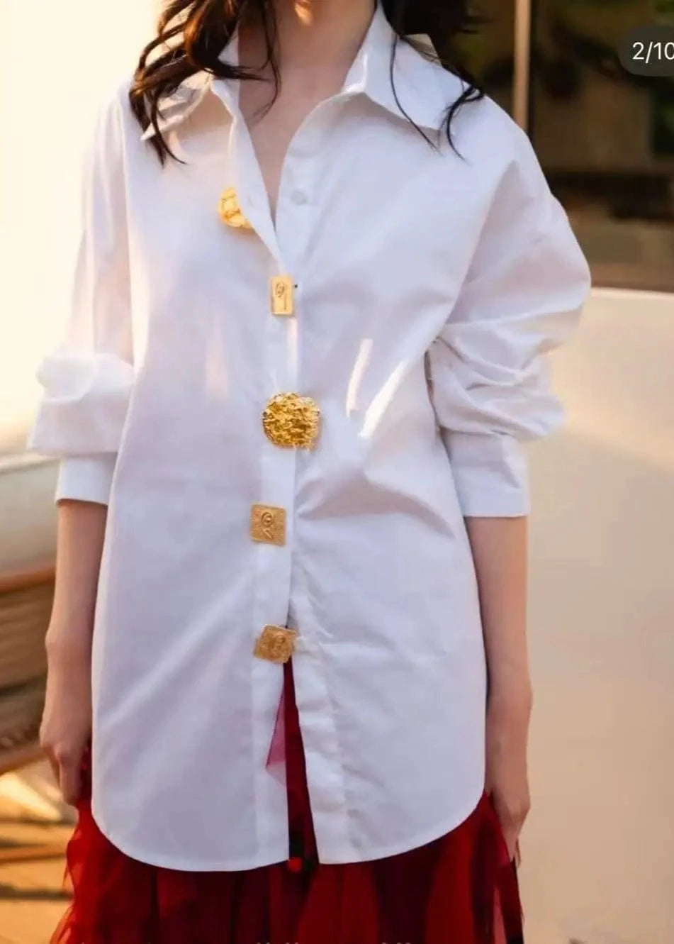 White shirt with gold buttons worn by a person, blurred background