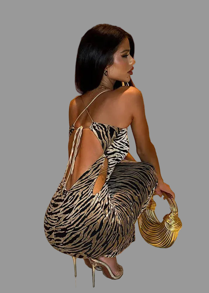 Woman in a zebra print dress holding a gold handbag in a room with wooden walls.