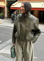 Woman in a green leather jacket and pants walking on a city street.