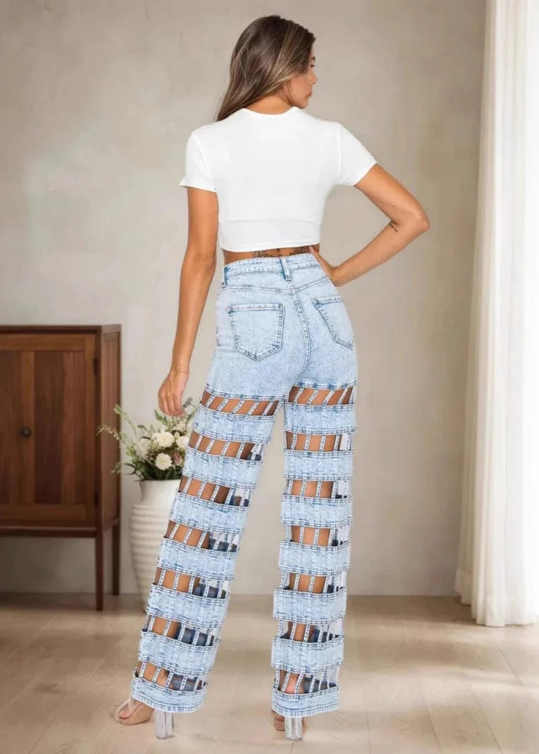 Woman wearing patterned jeans and a white top in a room with wooden furniture and flowers.