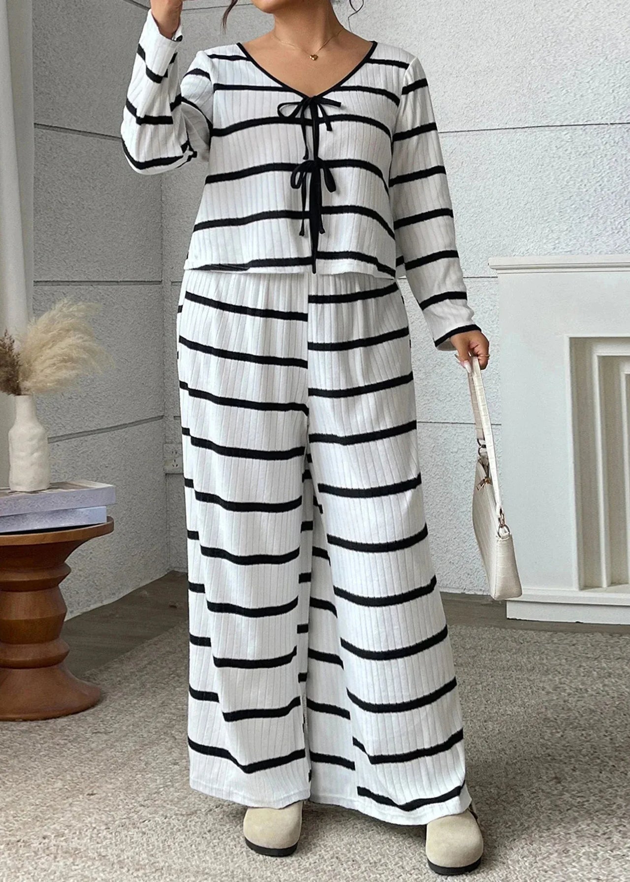Person wearing a black and white striped outfit in a room with a fireplace and wooden table.