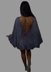 Person wearing a blue dress with an open back on a staircase.