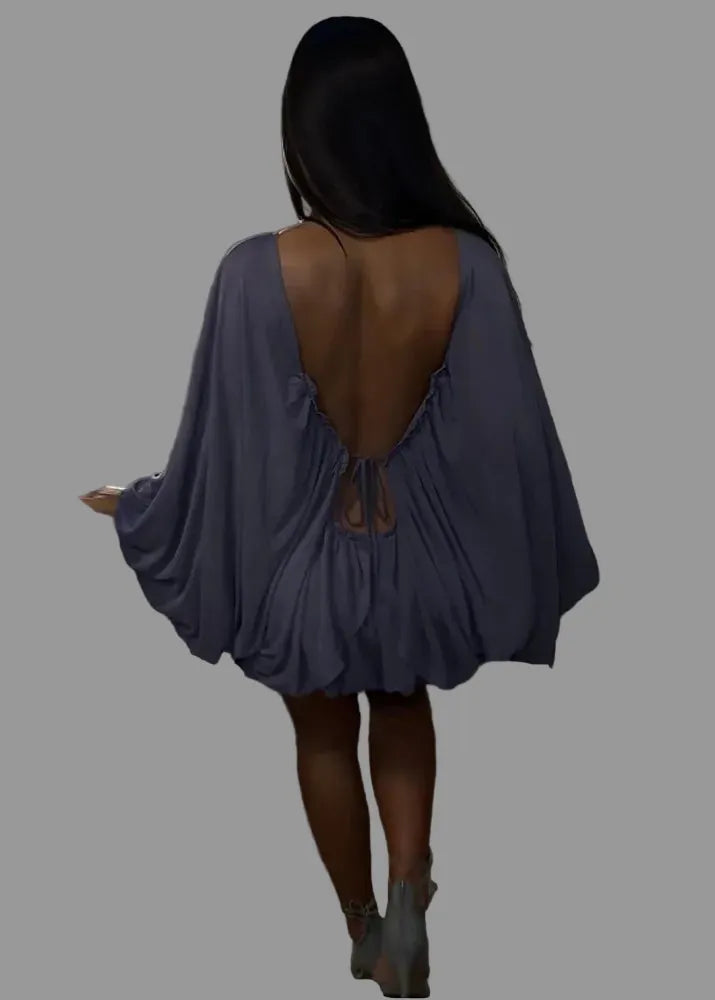 Person wearing a blue dress with an open back on a staircase.