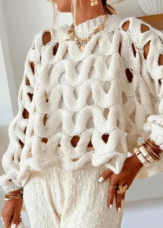 Person wearing a white knit sweater with cut-out design in an indoor setting