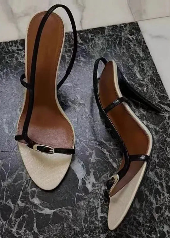 Pair of black and beige high-heeled sandals on a marble surface