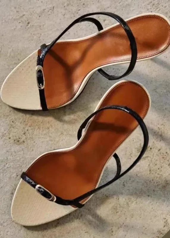 Pair of brown sandals with black straps on a textured surface