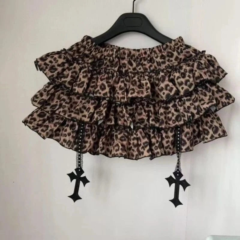 Leopard print top with ruffles and black cross decorations on a hanger against a white background