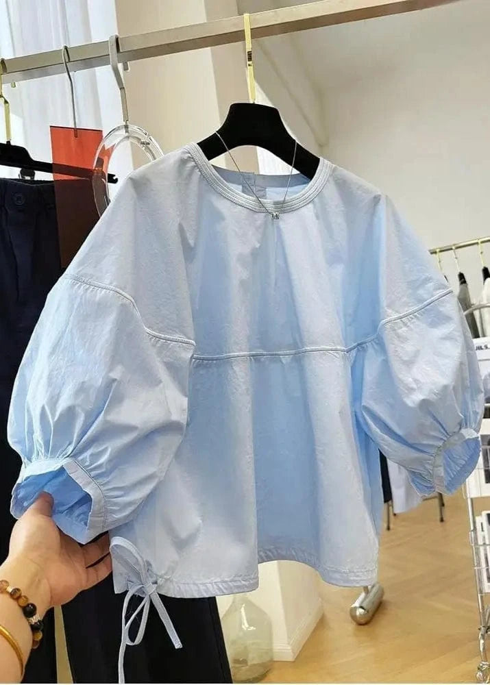 Light blue jacket with puff sleeves on a hanger in a store setting