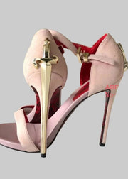 Pink high-heeled shoes with gold sword design on a wooden background, branded 'ABENGYA'.