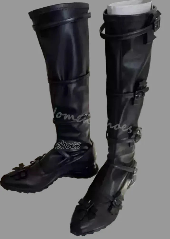 Black knee-high boots with buckles on a white surface