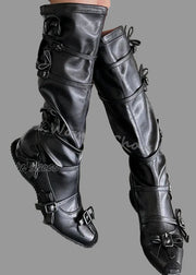 Black leather knee-high boots with buckles on a concrete floor.