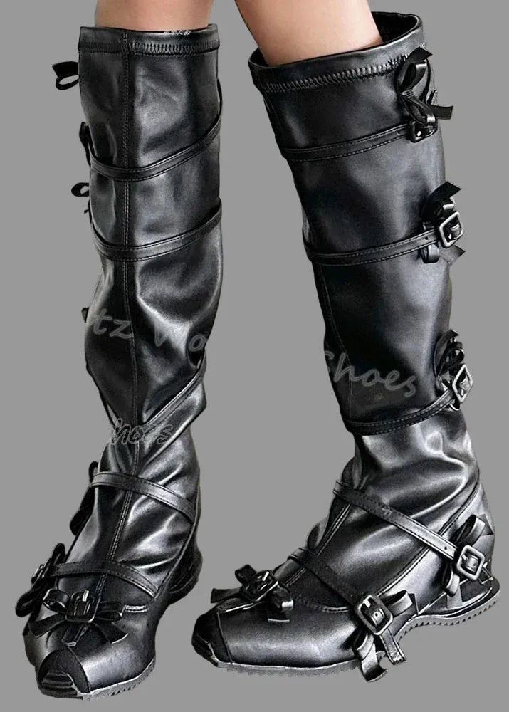 Black leather boots with buckles on a concrete floor.