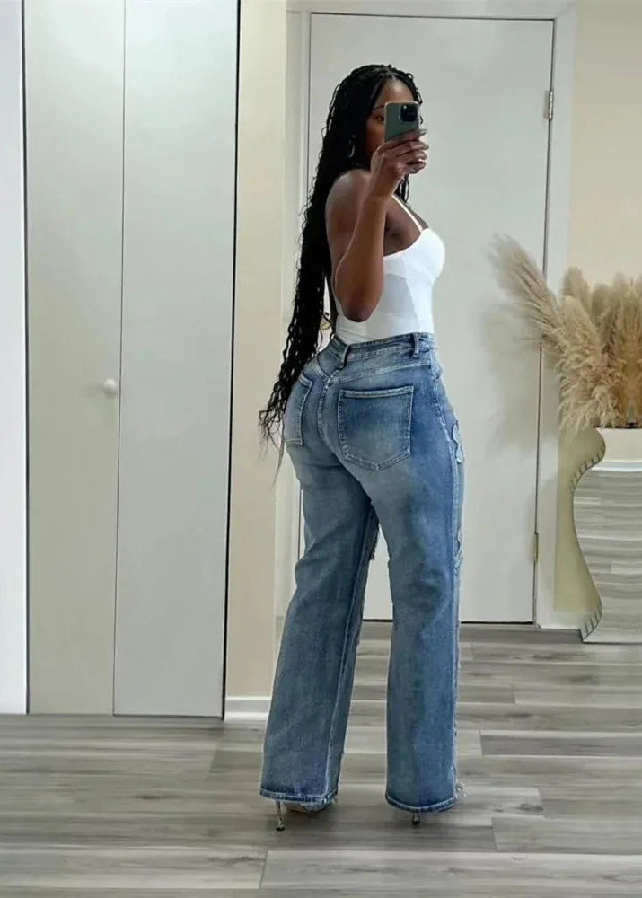 Person wearing a white top and blue jeans taking a mirror selfie.