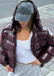 Person wearing a brown puffer jacket and gray cap on a sidewalk.