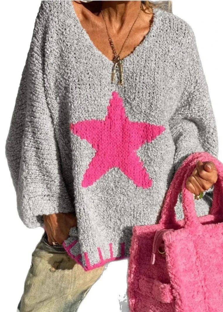 Person wearing a gray sweater with a pink star design, holding a pink bag.