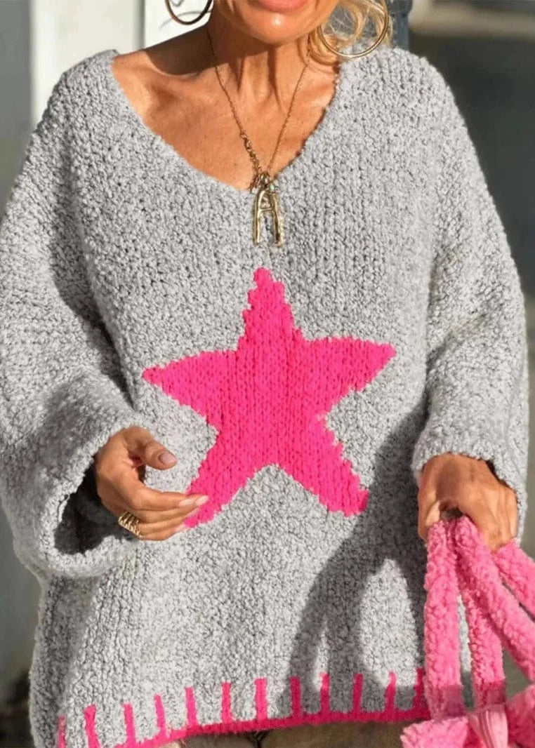 Person wearing a gray sweater with a pink star design, holding a matching pink bag.