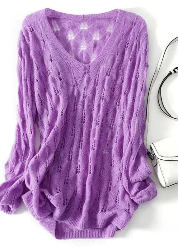 Purple sweater on a white background with a silver handbag.
