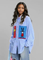 Person wearing a light blue shirt with colorful graphic designs on a gray background