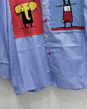 Blue striped shirt with cartoon character patches on a gray surface