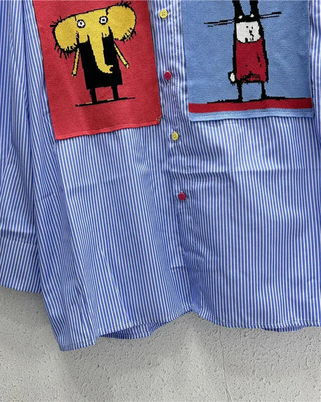 Blue striped shirt with cartoon character patches on a gray surface