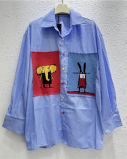 Blue striped shirt with cartoon character patches on a gray background
