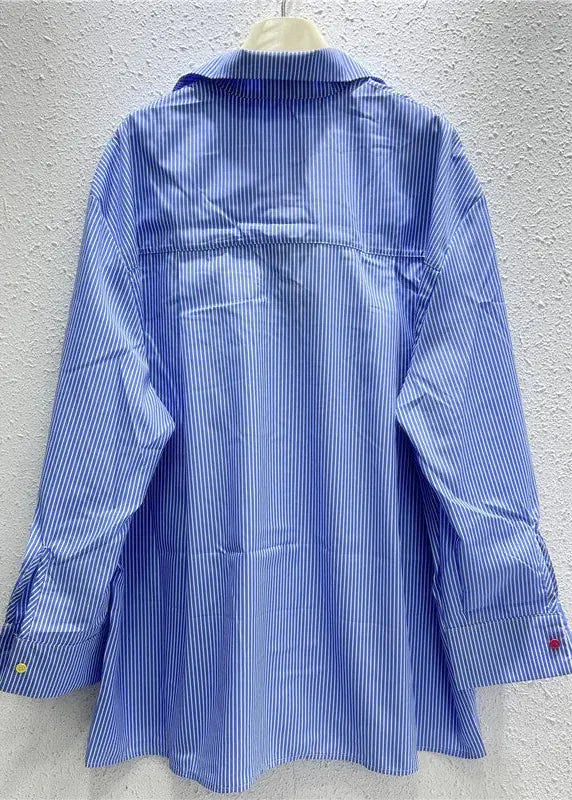 Blue striped shirt on a hanger against a gray textured wall